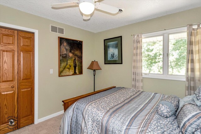 bedroom featuring light colored carpet, visible vents, a ceiling fan, a textured ceiling, and baseboards