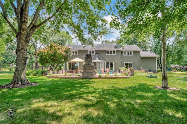 rear view of house with a patio, a yard, and a chimney