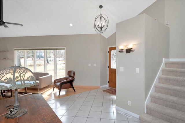 living room featuring light tile patterned floors, ceiling fan with notable chandelier, baseboards, vaulted ceiling, and stairway