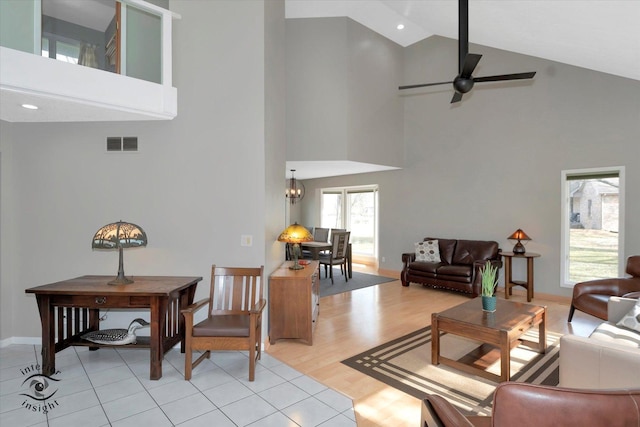 living room with ceiling fan with notable chandelier, baseboards, visible vents, and light wood-style floors