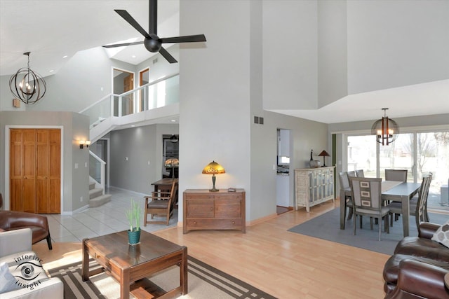 living area with baseboards, visible vents, stairway, wood finished floors, and ceiling fan with notable chandelier