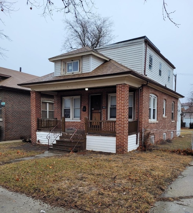 7655 S Clyde Ave, Chicago, IL 60649 - bungalow with a porch, brick siding, roof with shingles, and a front lawn