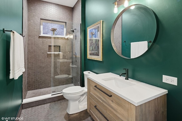 bathroom featuring vanity, toilet, and a tile shower