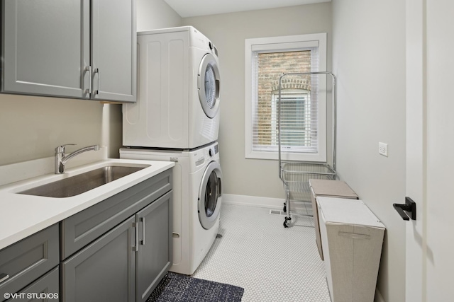 clothes washing area featuring cabinets, stacked washer / drying machine, and sink