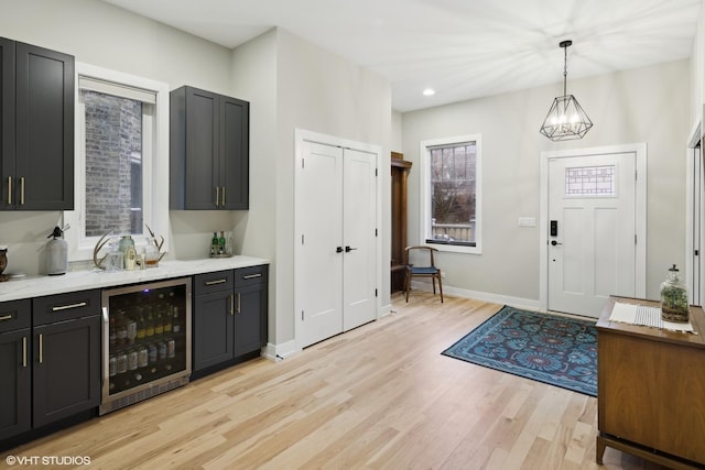 entrance foyer featuring indoor bar, an inviting chandelier, wine cooler, and light hardwood / wood-style floors