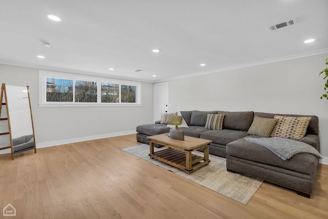 living room featuring ornamental molding, light wood-style flooring, visible vents, and baseboards