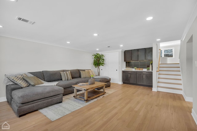 living room with light wood finished floors, recessed lighting, visible vents, ornamental molding, and stairs