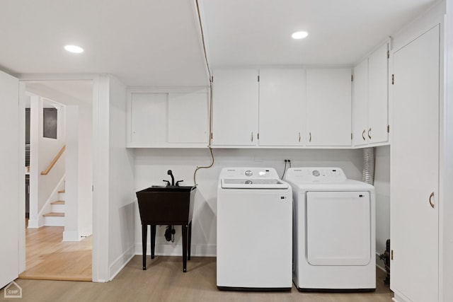 laundry area with cabinet space, light wood finished floors, baseboards, washing machine and clothes dryer, and recessed lighting