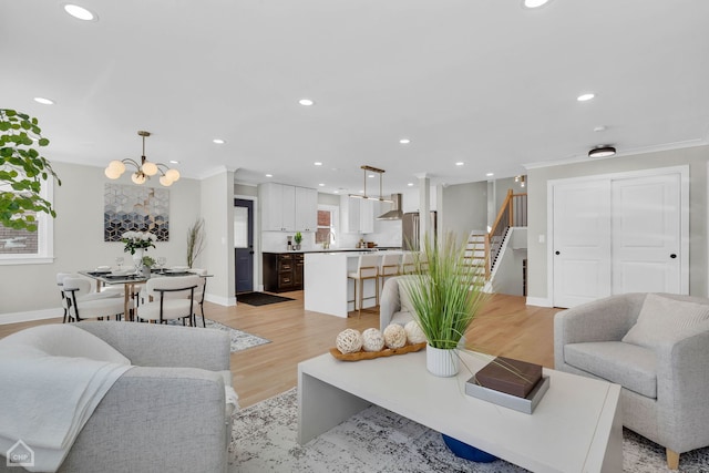 living area with light wood-style floors, stairs, ornamental molding, and recessed lighting