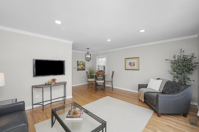 living room with hardwood / wood-style flooring, crown molding, and a chandelier