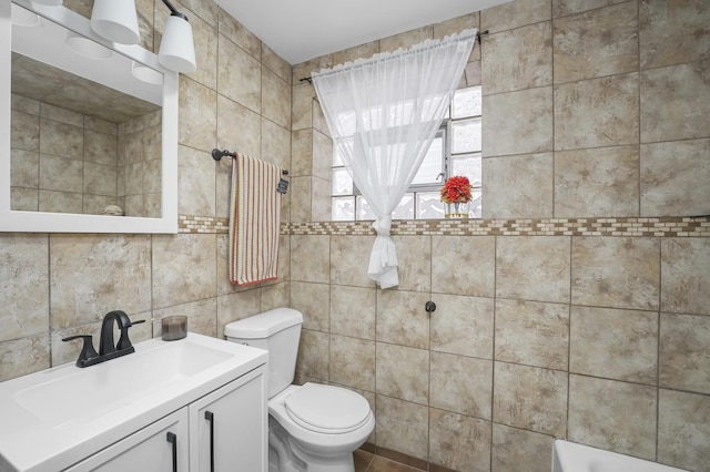 bathroom featuring vanity, a bath, tile walls, and toilet