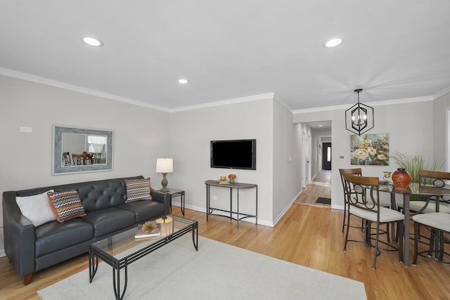 living room with a notable chandelier, crown molding, and light hardwood / wood-style floors