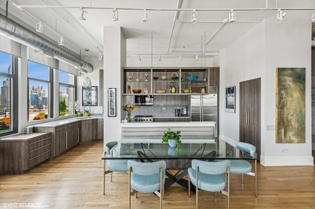 interior space with light hardwood / wood-style flooring, decorative backsplash, dark brown cabinets, and stainless steel appliances