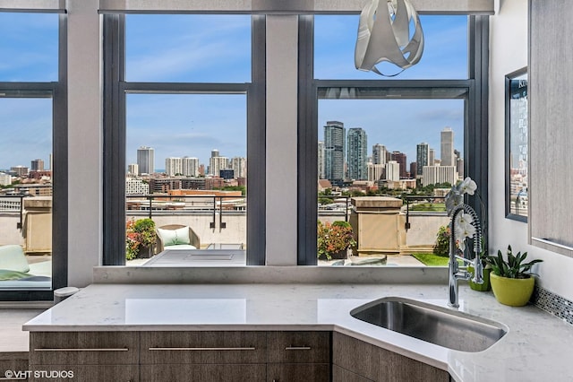 kitchen featuring a healthy amount of sunlight, sink, light stone counters, and dark brown cabinetry