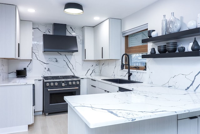 kitchen with sink, white cabinetry, tasteful backsplash, light stone counters, and high end stove