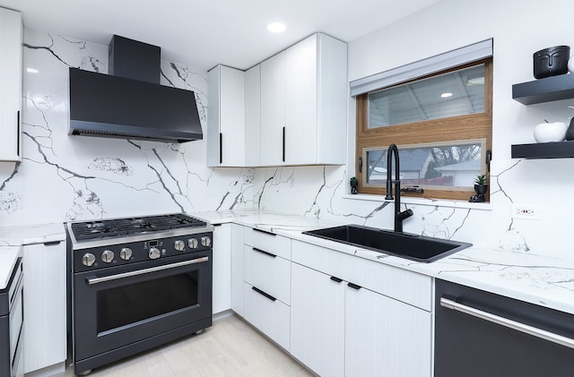 kitchen with wall chimney exhaust hood, high end stainless steel range, sink, white cabinetry, and dishwasher