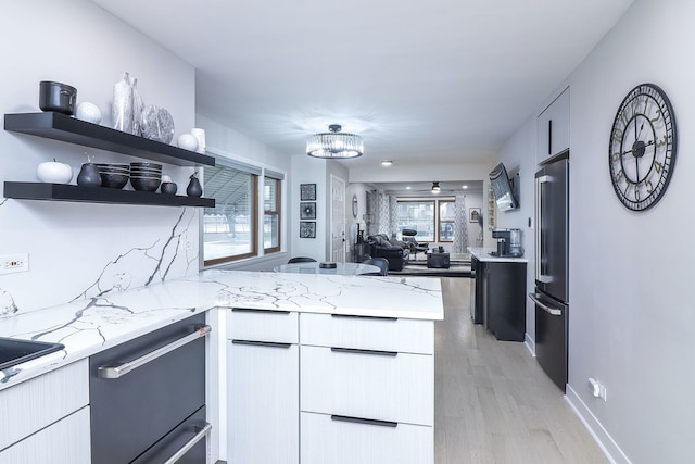 kitchen with light stone countertops, high end fridge, black dishwasher, and kitchen peninsula