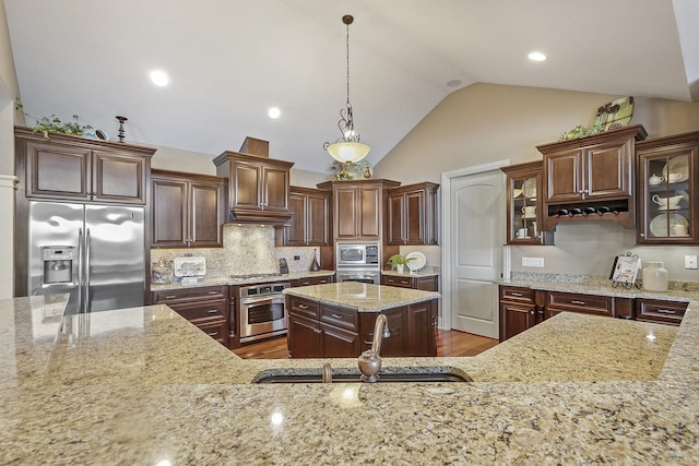 kitchen featuring appliances with stainless steel finishes, decorative light fixtures, sink, dark brown cabinetry, and light stone counters