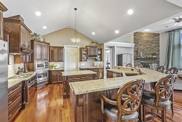 kitchen featuring a large island with sink, appliances with stainless steel finishes, dark hardwood / wood-style floors, a kitchen breakfast bar, and pendant lighting