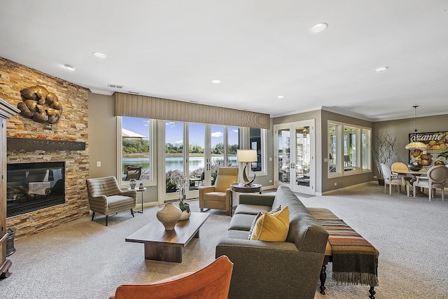 carpeted living room featuring a fireplace, ornamental molding, and a water view