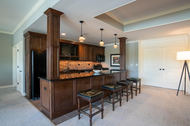 kitchen featuring pendant lighting, light colored carpet, a breakfast bar, and black appliances