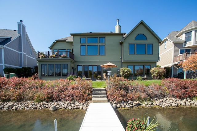 rear view of property featuring a water view and a balcony