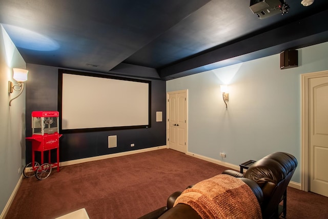 cinema featuring a raised ceiling and dark carpet