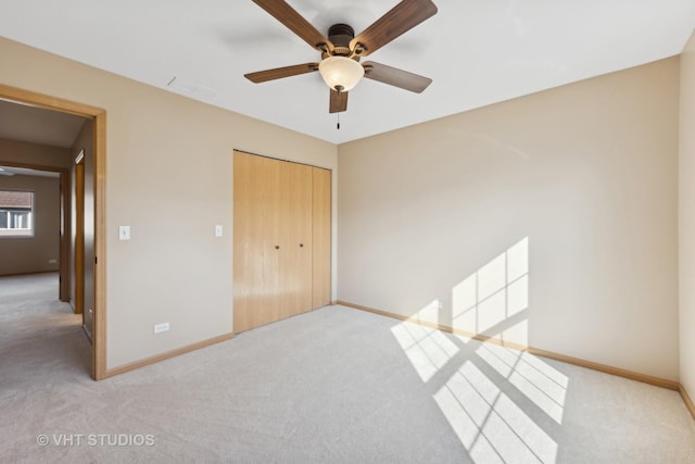 unfurnished bedroom featuring ceiling fan, light colored carpet, and a closet