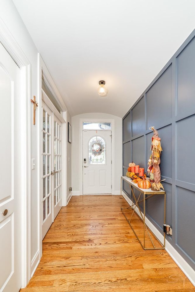 doorway with french doors, vaulted ceiling, and light wood-type flooring