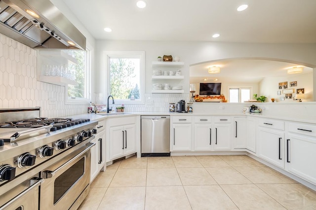 kitchen featuring white cabinetry, sink, decorative backsplash, stainless steel appliances, and wall chimney range hood