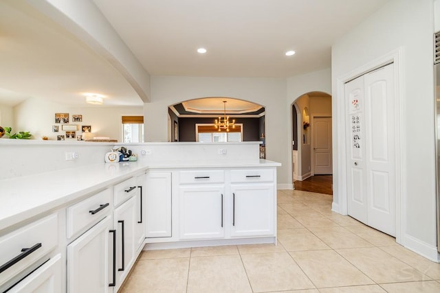 kitchen with white cabinetry, light tile patterned flooring, a notable chandelier, and kitchen peninsula