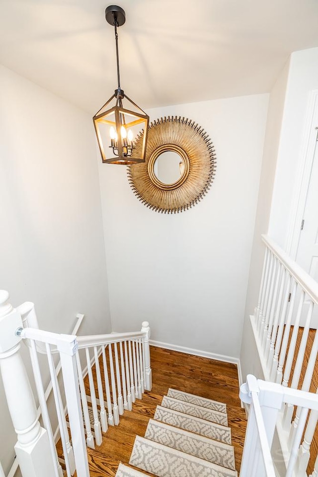 stairs with wood-type flooring and a chandelier