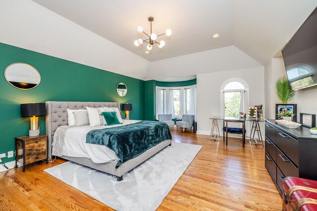 bedroom with lofted ceiling, an inviting chandelier, and light wood-type flooring