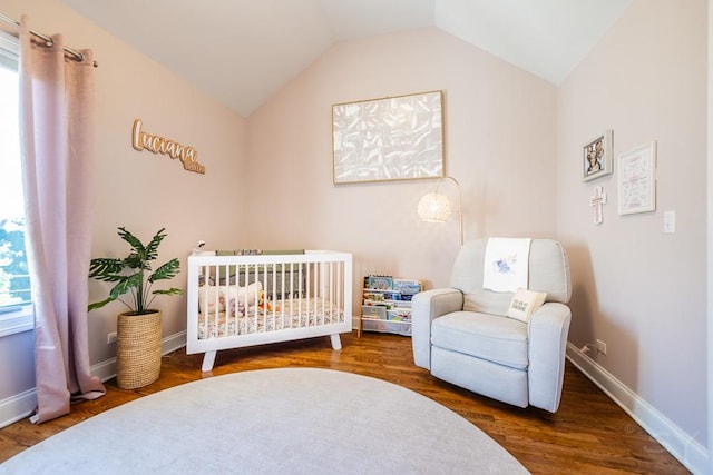 bedroom featuring lofted ceiling, hardwood / wood-style floors, and a nursery area