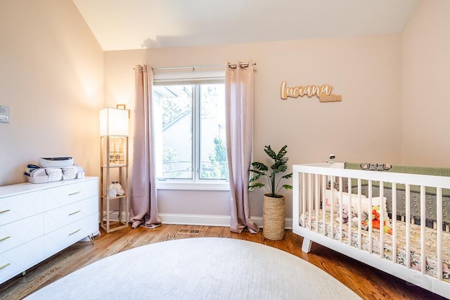 bedroom with a nursery area and hardwood / wood-style floors