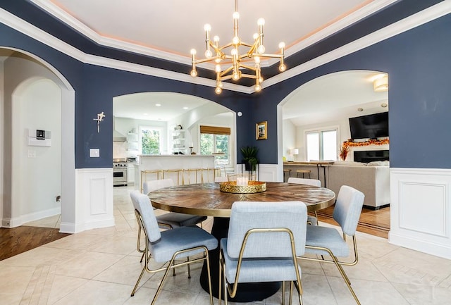 dining space with a raised ceiling, light tile patterned flooring, a healthy amount of sunlight, and ornamental molding