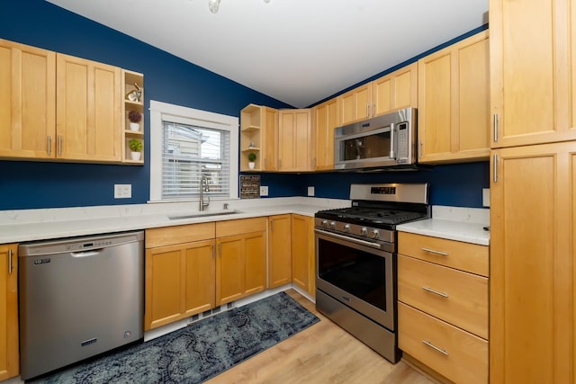 kitchen with light wood-type flooring, stainless steel appliances, sink, and light brown cabinets