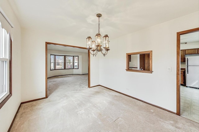 unfurnished room with light colored carpet and a chandelier