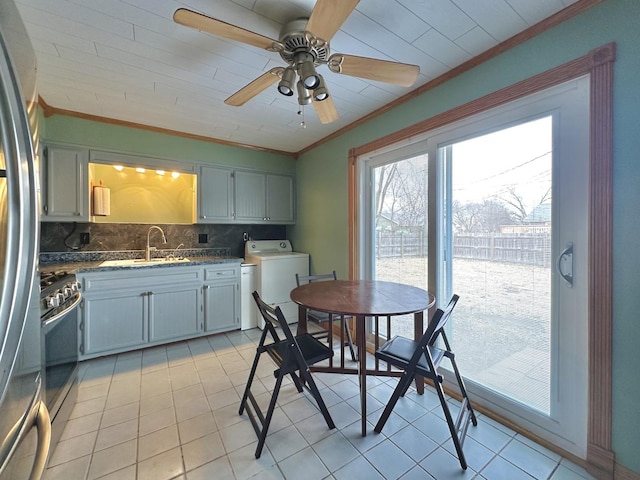 kitchen with sink, crown molding, washer and clothes dryer, appliances with stainless steel finishes, and tasteful backsplash