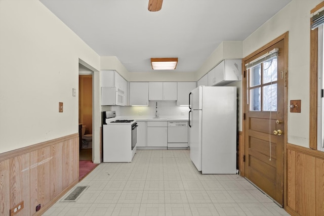 kitchen with white cabinetry, white appliances, and wooden walls