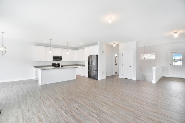 kitchen featuring pendant lighting, white cabinetry, appliances with stainless steel finishes, and a kitchen island with sink