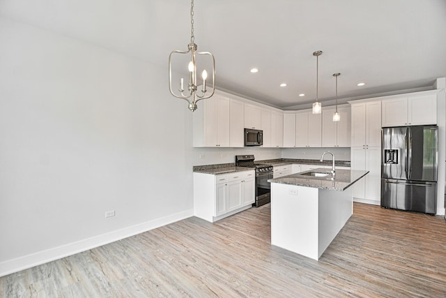 kitchen with sink, decorative light fixtures, an island with sink, stainless steel appliances, and white cabinets