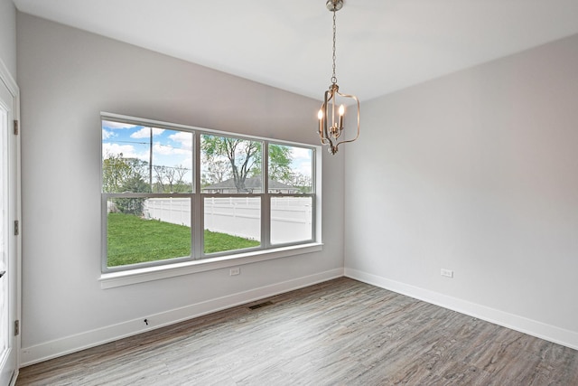 spare room with hardwood / wood-style flooring and a notable chandelier