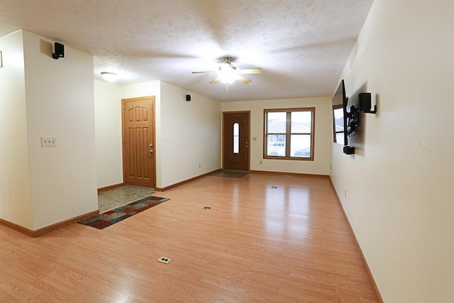 foyer entrance with ceiling fan, a textured ceiling, and light hardwood / wood-style floors