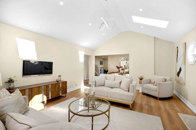 living room with vaulted ceiling with skylight and light wood-type flooring