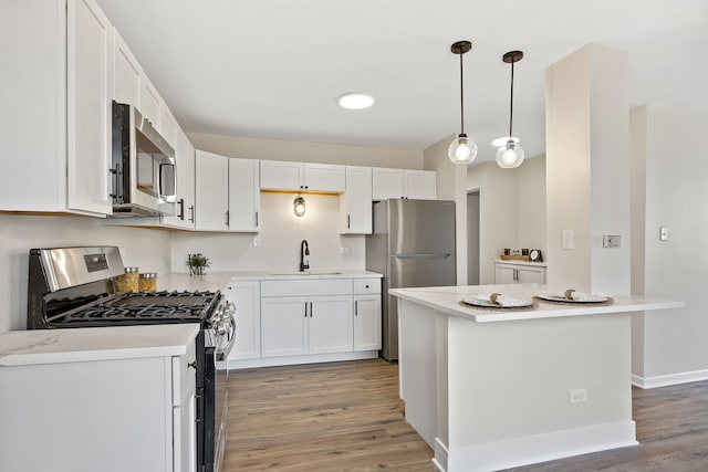 kitchen with pendant lighting, stainless steel appliances, sink, and white cabinets