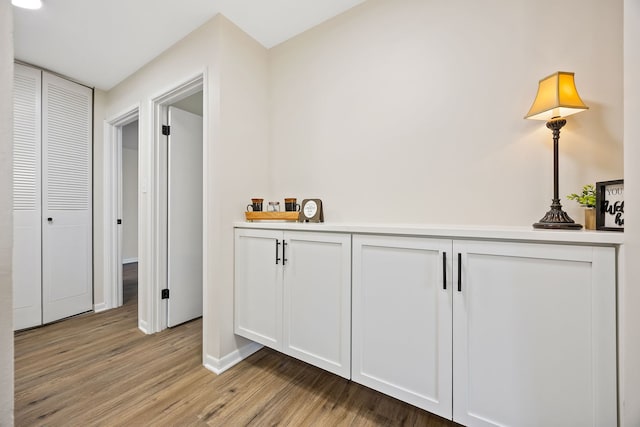 interior space with white cabinetry, pendant lighting, and light wood-type flooring