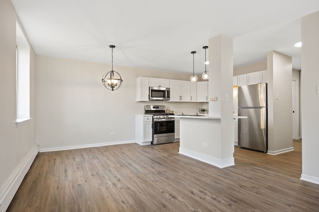 kitchen with baseboard heating, appliances with stainless steel finishes, decorative light fixtures, and white cabinets