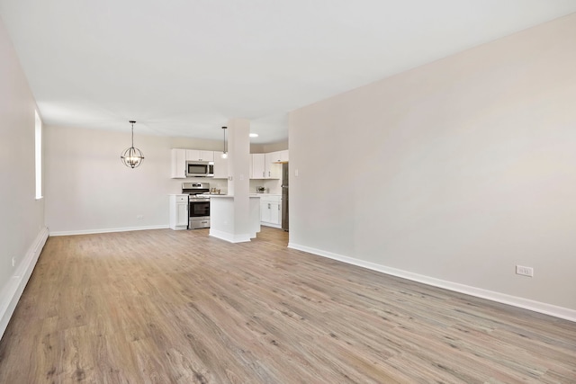 unfurnished living room with a notable chandelier and light wood-type flooring