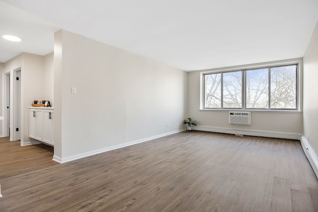 spare room with a wall unit AC, light hardwood / wood-style floors, and baseboard heating